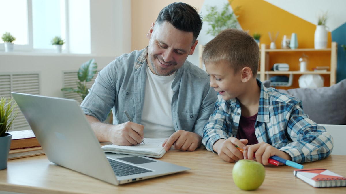 A parent and child looking at a laptop together at the kitchen table