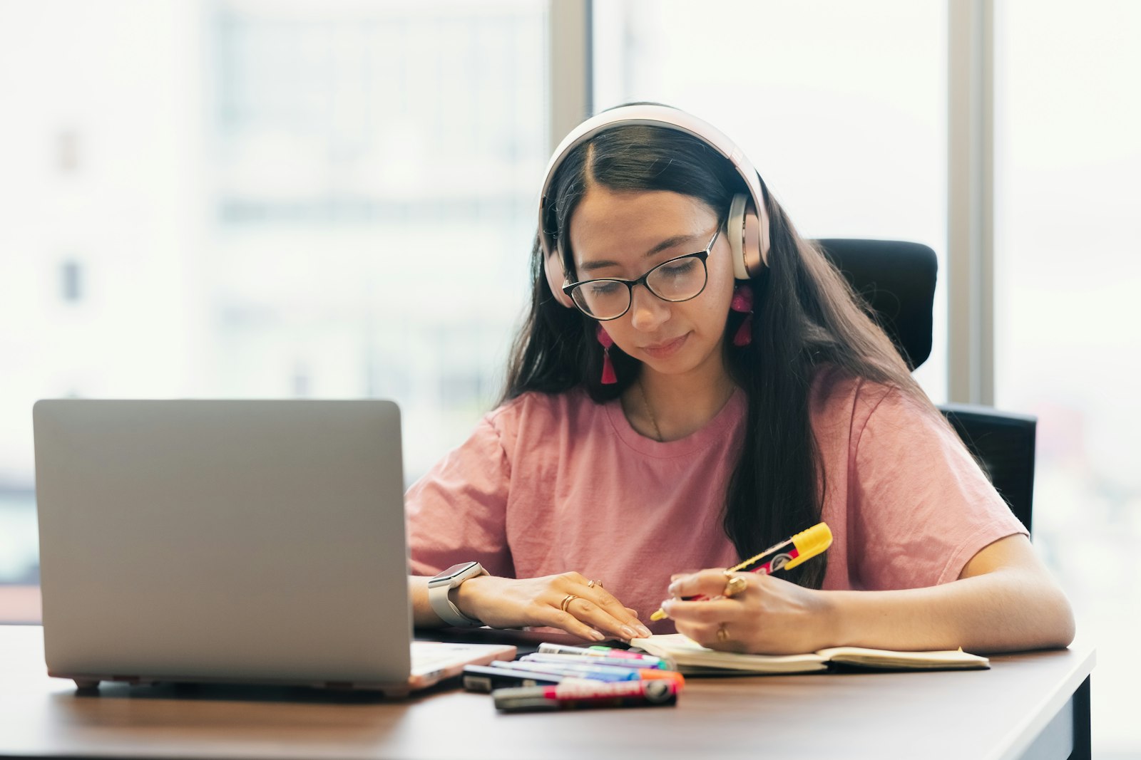 A high school student studying at a desk with a laptop and notes
